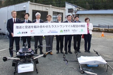 物流専用ドローンPD4B-M-ANとAirTruckを前に代表者による集合写真